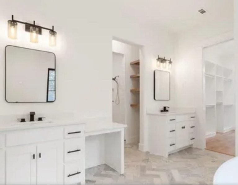 Bright, modern bathroom with two mirrors, white cabinetry, and a spacious layout.
